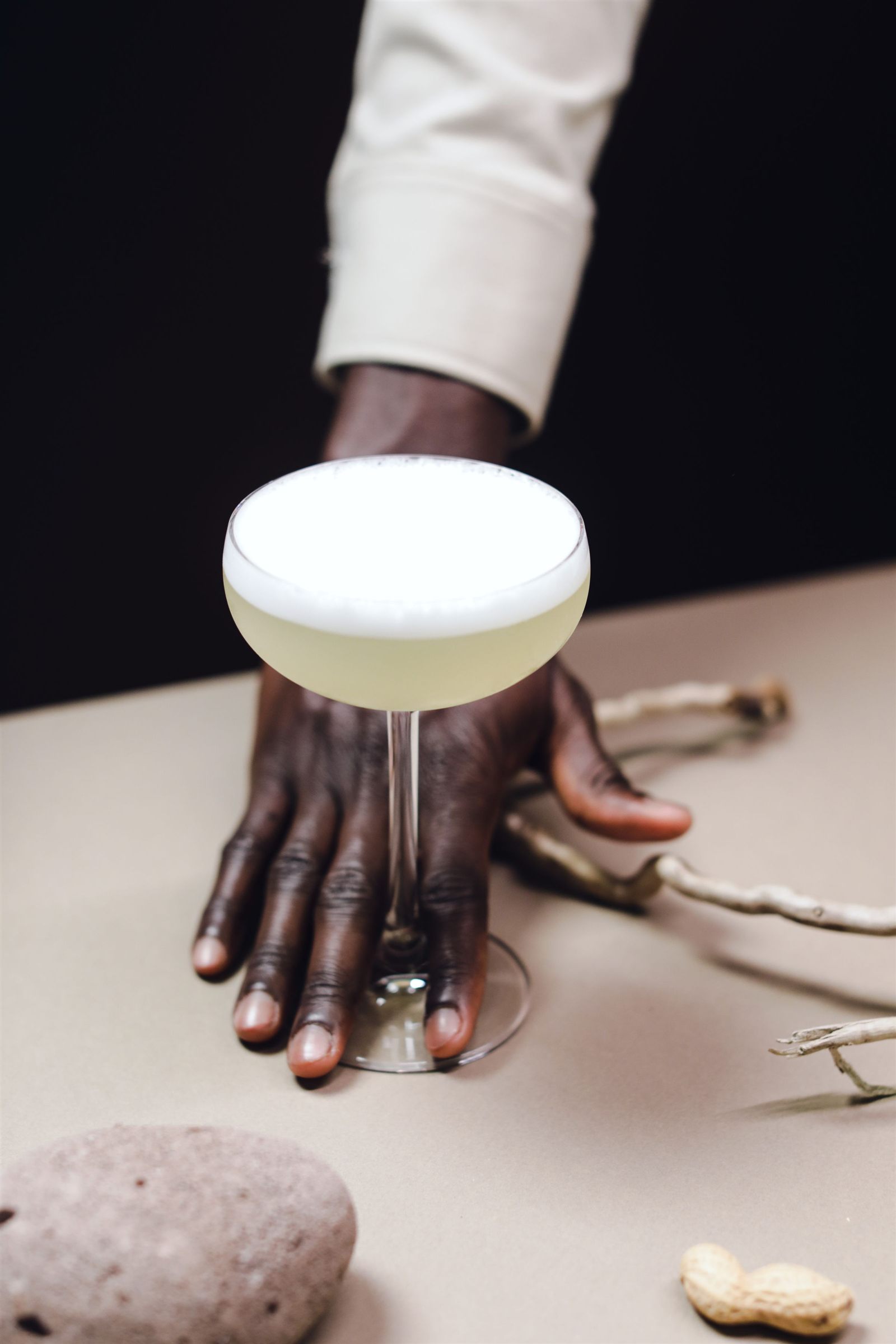 A hand resting beside a frothy cocktail on a table